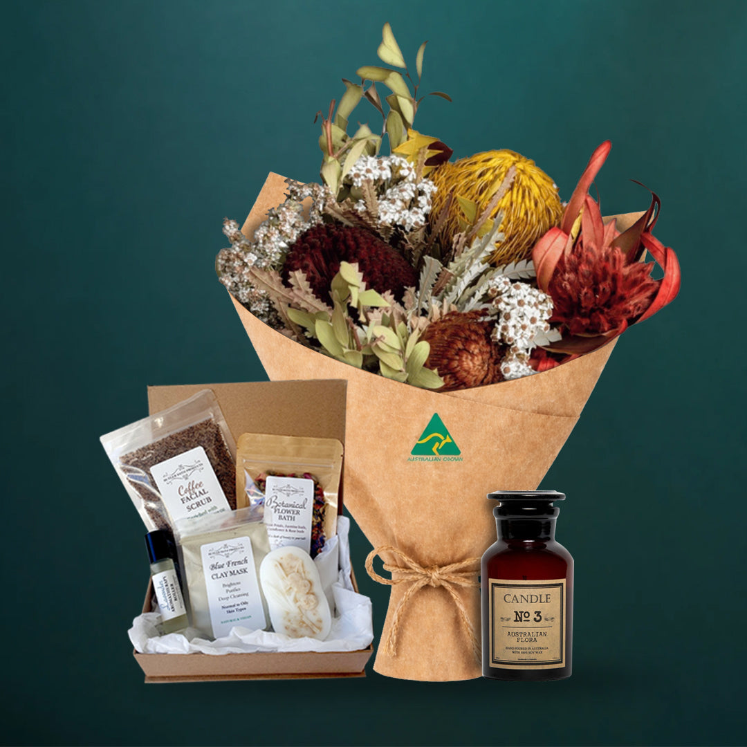 Mustard dried native bouquet with an Australian Flora soy candle and a five-piece Butler Bath pamper set in a kraft gift box, on a dark teal background

