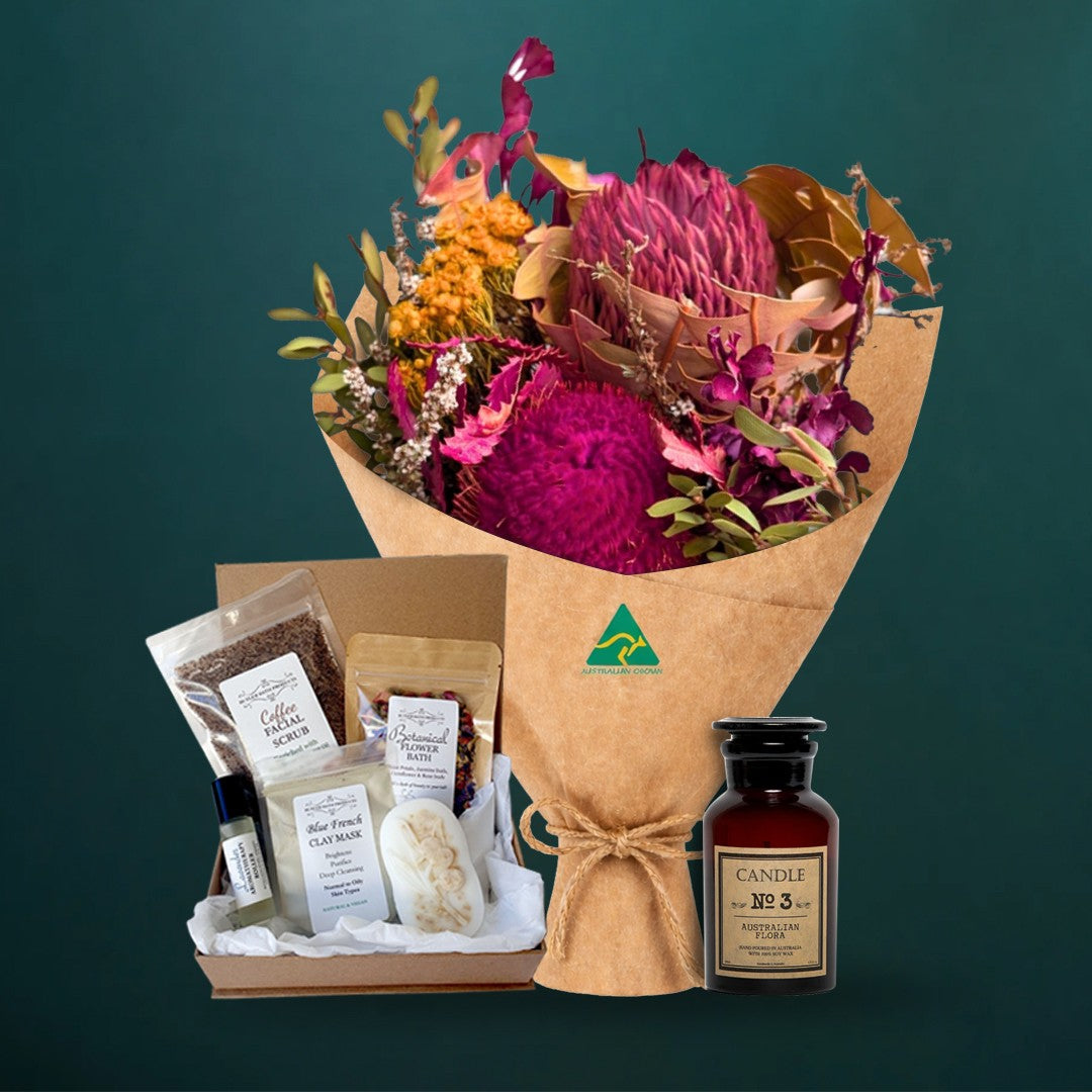 Hot pink dried native bouquet with an Australian Flora soy candle and a five-piece Butler Bath pamper set in a kraft gift box, on a dark teal background